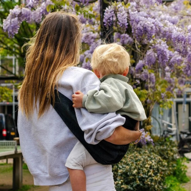 Child being carried in the Wildride Toddler Carrier in black corduroy