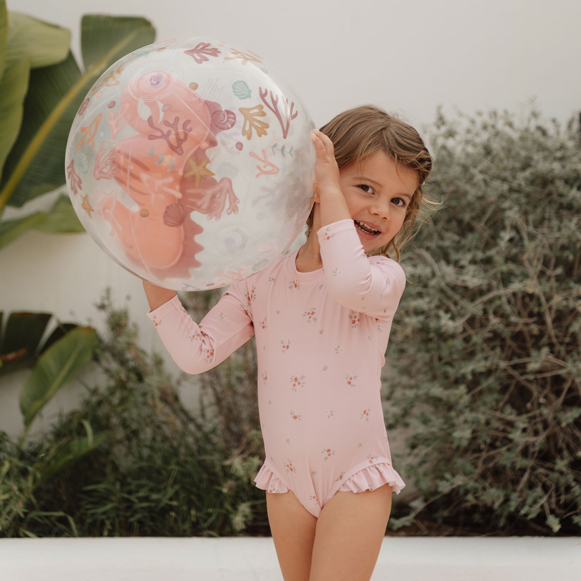 Child holding aloft Little Dutch Beach Ball in pink