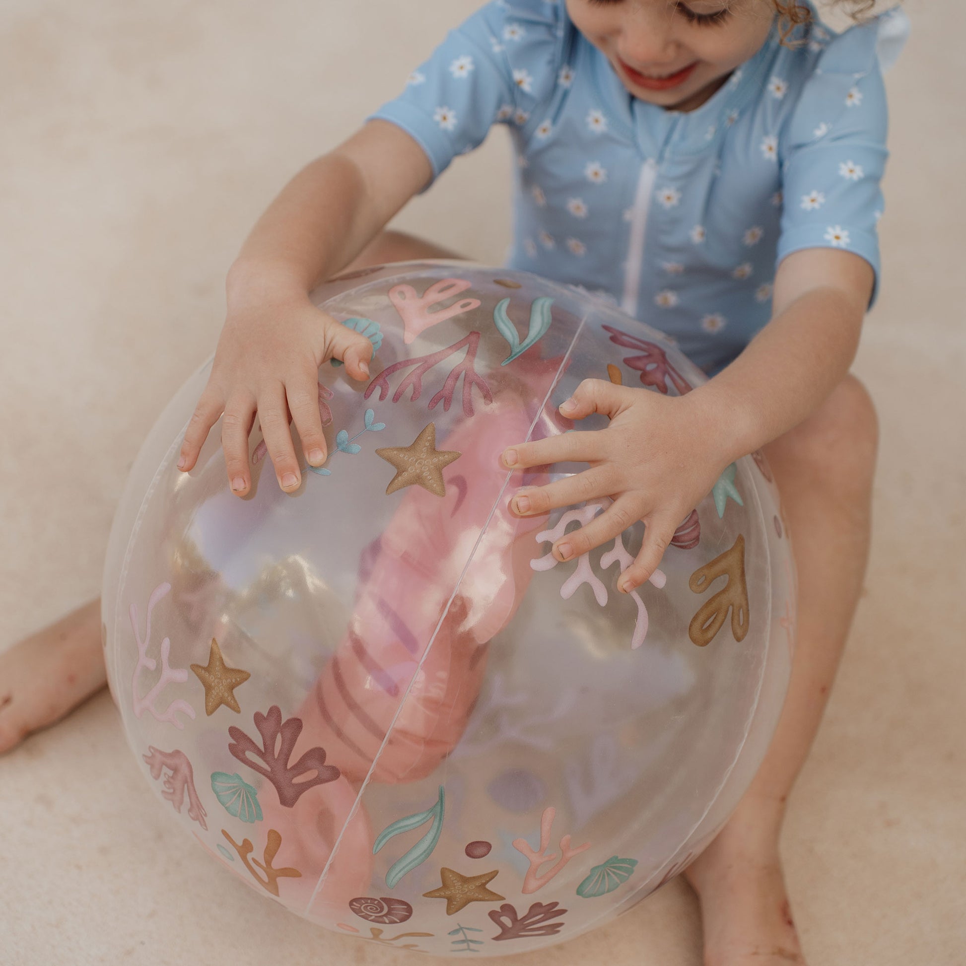 Child sitting with Little Dutch 3D beach ball in pink