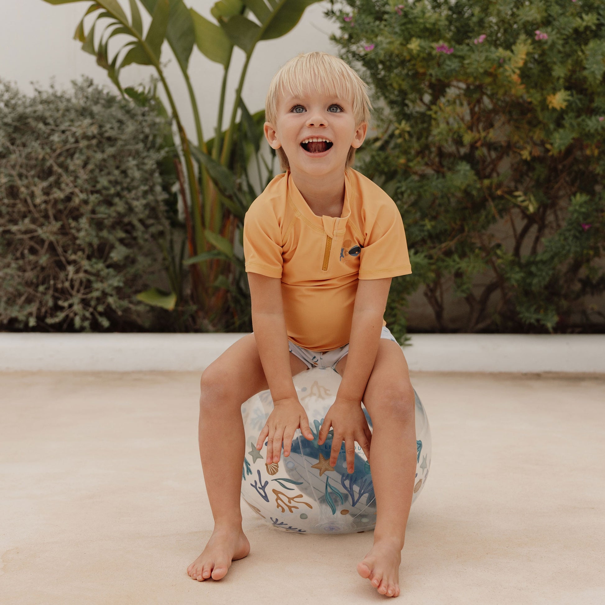 Laughing child sitting on Little Dutch 3D Beach Ball in blue
