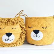 Two yellow lion-themed baskets with faces on a white surface.