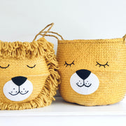 Two yellow lion-themed baskets with faces on a white surface.