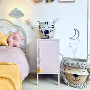 Children's bedroom with a bed, nightstand, and decorative items on a light blue wall.