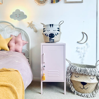 Children's bedroom with a bed, nightstand, and decorative items on a light blue wall.