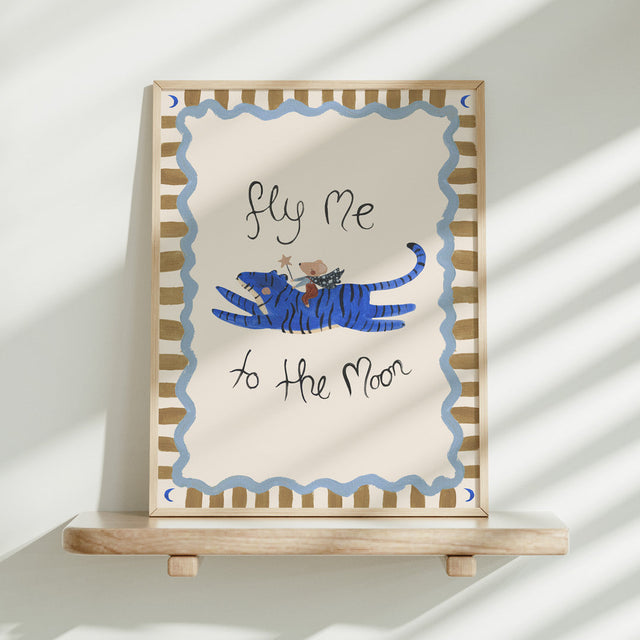 Framed artwork with a blue tiger and text 'fly me to the moon' on a white background