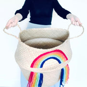 Woman holding a large woven basket with a rainbow design on a white background
