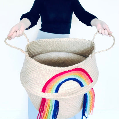 Woman holding a large woven basket with a rainbow design on a white background