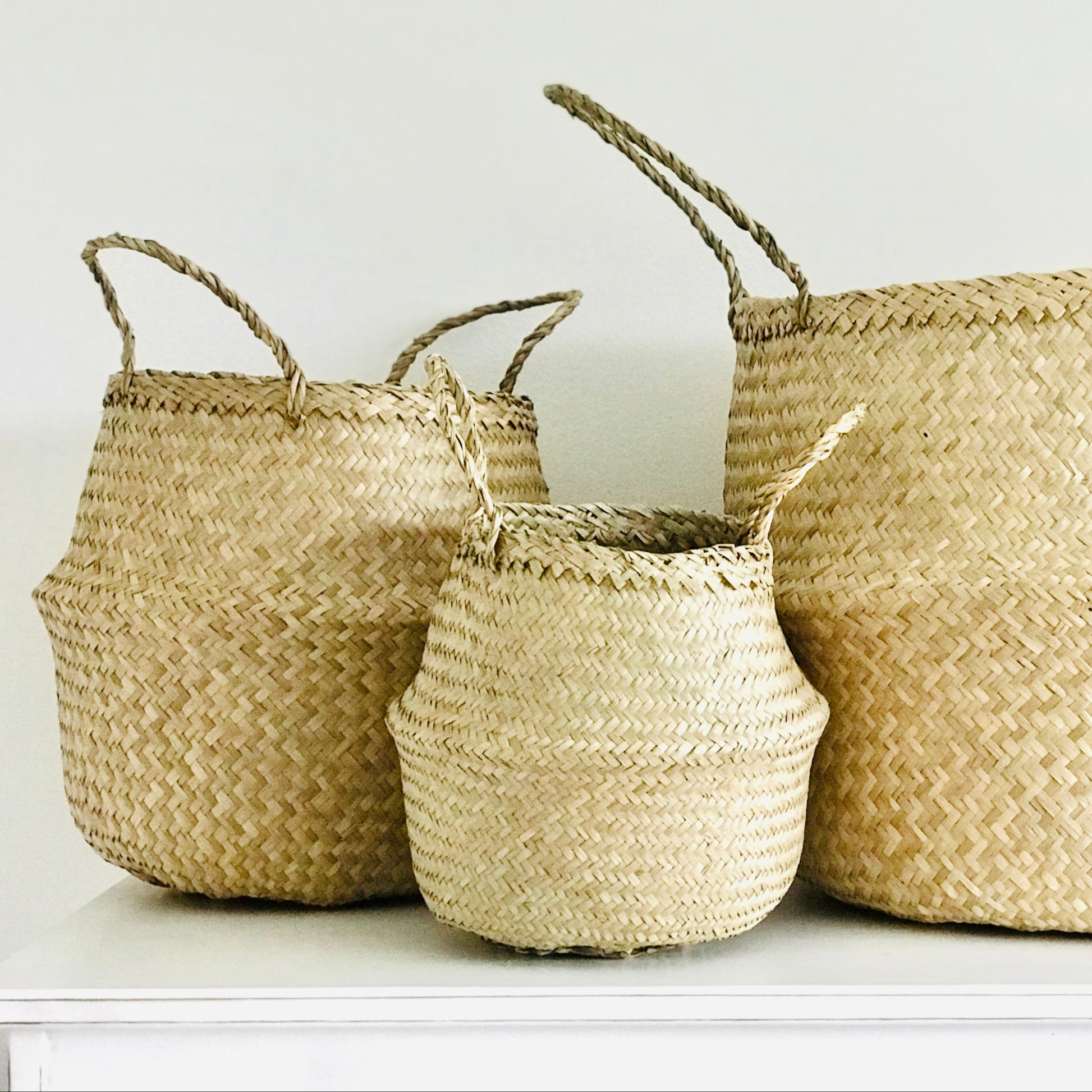 Three woven baskets of different sizes on a white surface with a white background
