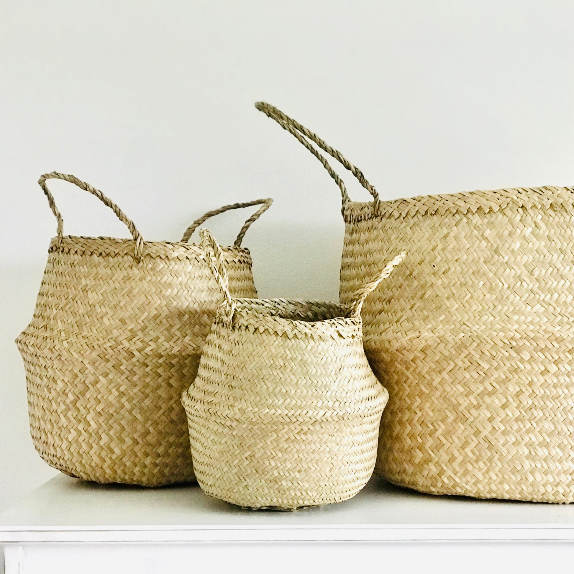 Three woven baskets of different sizes on a white surface with a white background