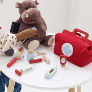 Le Toy Van Vintage Doctor Roleplay Wooden Kit with a hippo, medical instruments, and a bag on a white table. 