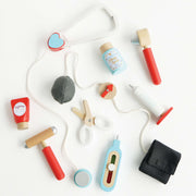 Le Toy Van Vintage Wooden Doctor's Kit with stethoscope, thermometer, needle, blood pressure gauge, ear scope, reflex hammer, surgical scissors, and medicine bottles. 