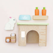 Le Toy Van Dolls House Pet Set, featuring a wooden kennel, a rabbit, two bunnies, a cat-scratching post, and a pet bowl, crafted from sustainable wood and decorated with non-toxic paints. 