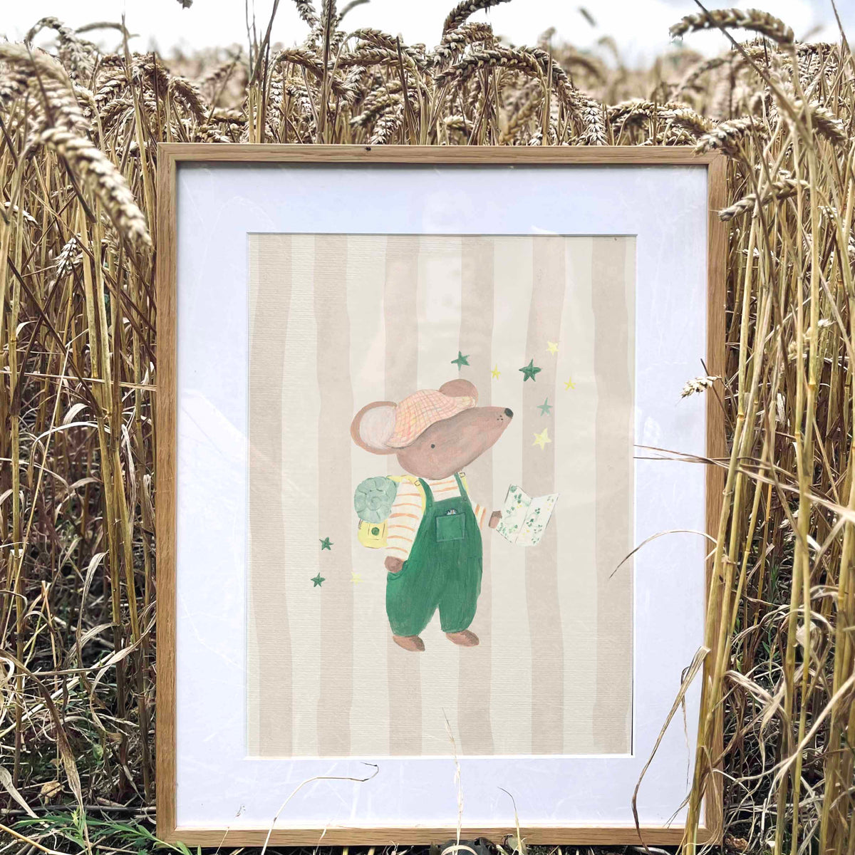 Framed illustration of a mouse in overalls standing in a field of wheat.