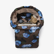 A padded storage pouch or bag shown from above on a plain white background. The exterior has a dark brown base with a blue floral print, and the interior is lined in tan.