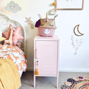 Children's room with a pink locker, unicorn-themed basket, and decorative wall art.