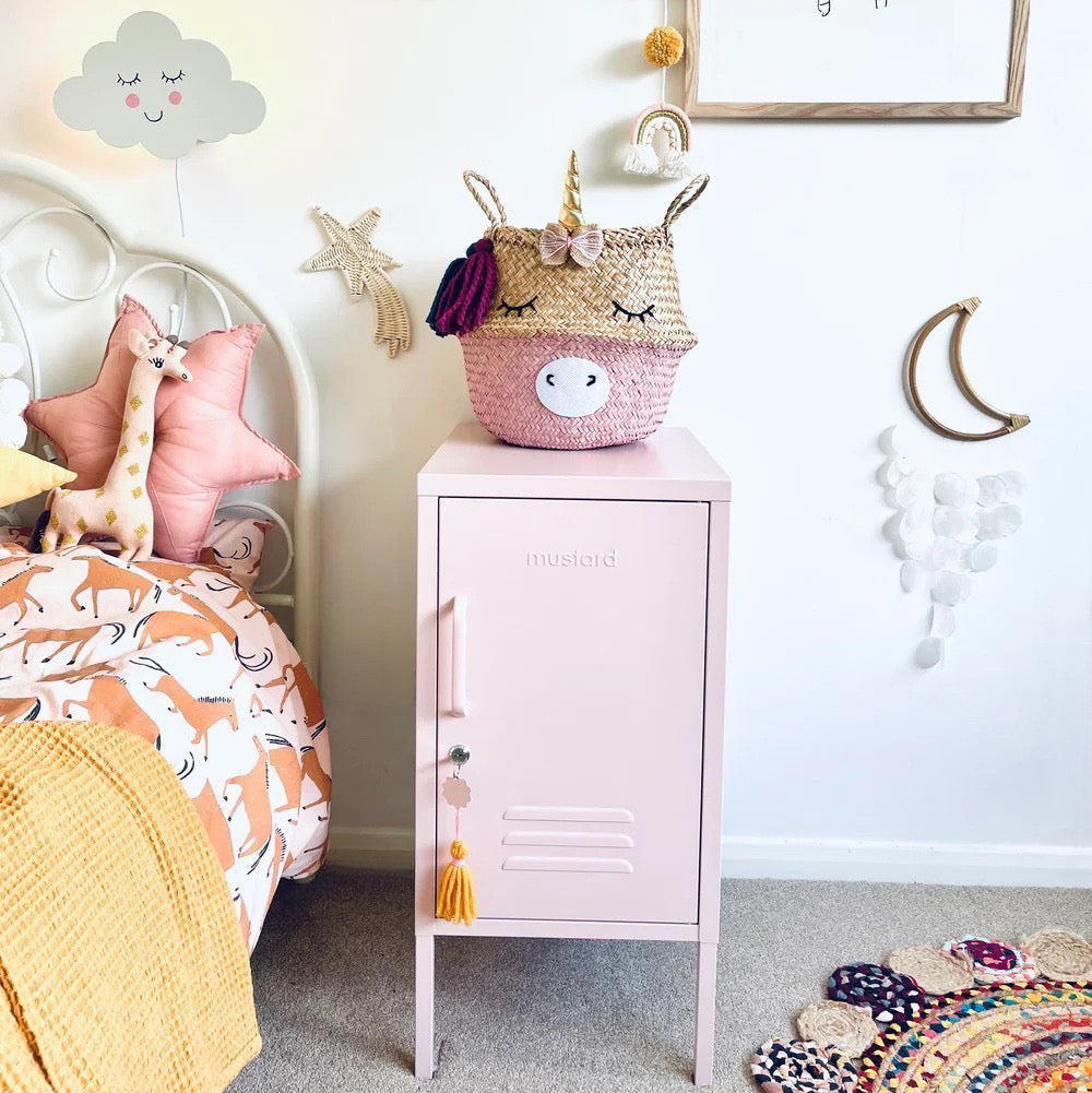 Children's room with a pink locker, unicorn-themed basket, and decorative wall art.