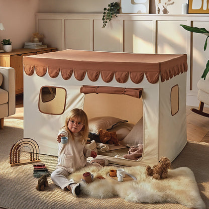 Child playing inside a play tent in a cosy room with toys and furniture.