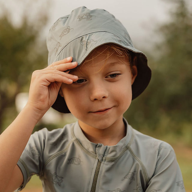 Little Boy Wearing The Little Dutch - Reversible Bucket Hat In Turtle Island Print