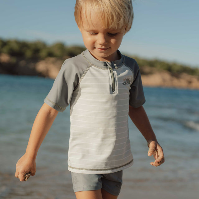 Little Boy Wearing The Little Dutch Swim T-shirt In Fresh Greens Walking On The Beach