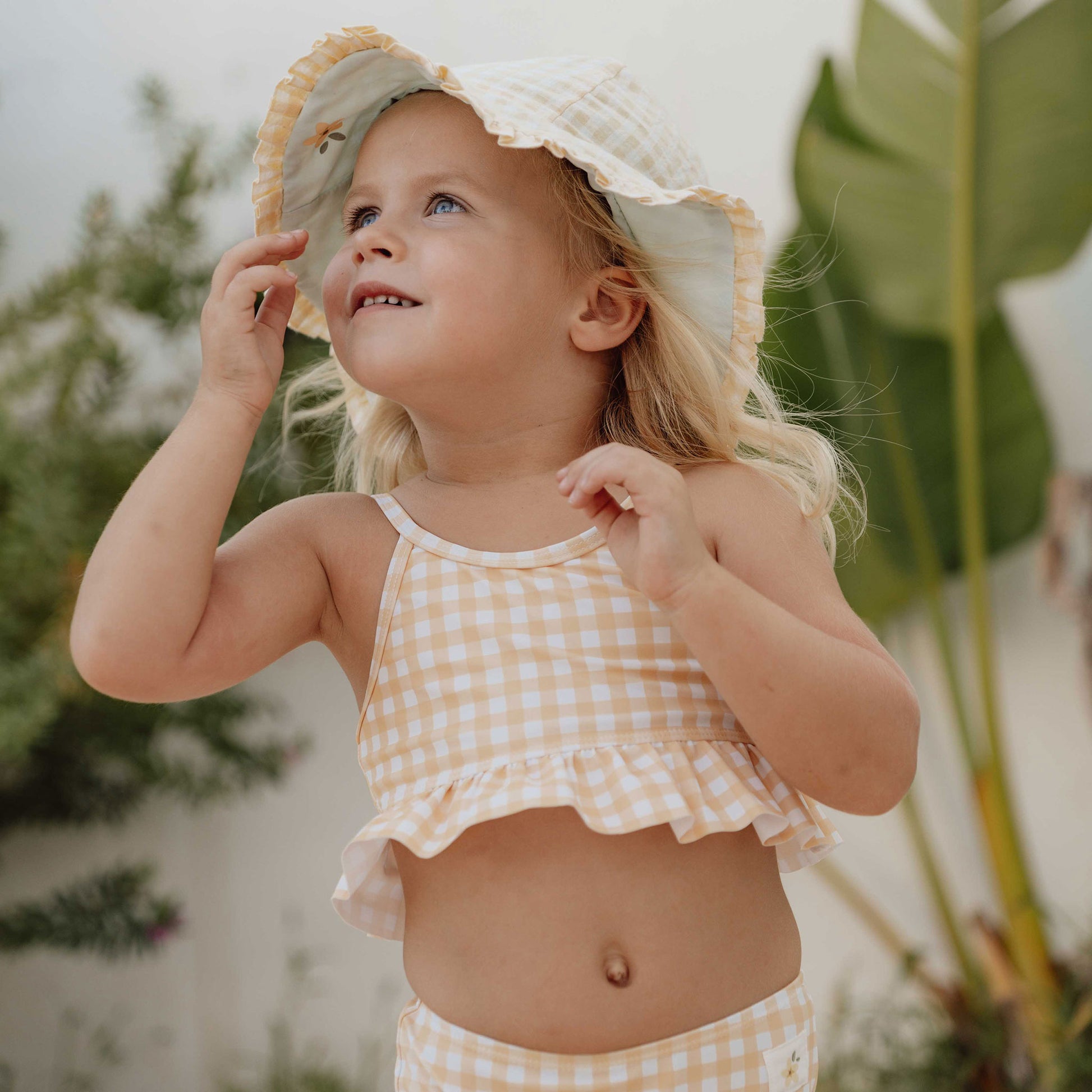 Little girl wearing Little Dutch Reversible Sun Hat In Sea Green & Sunshine Check
