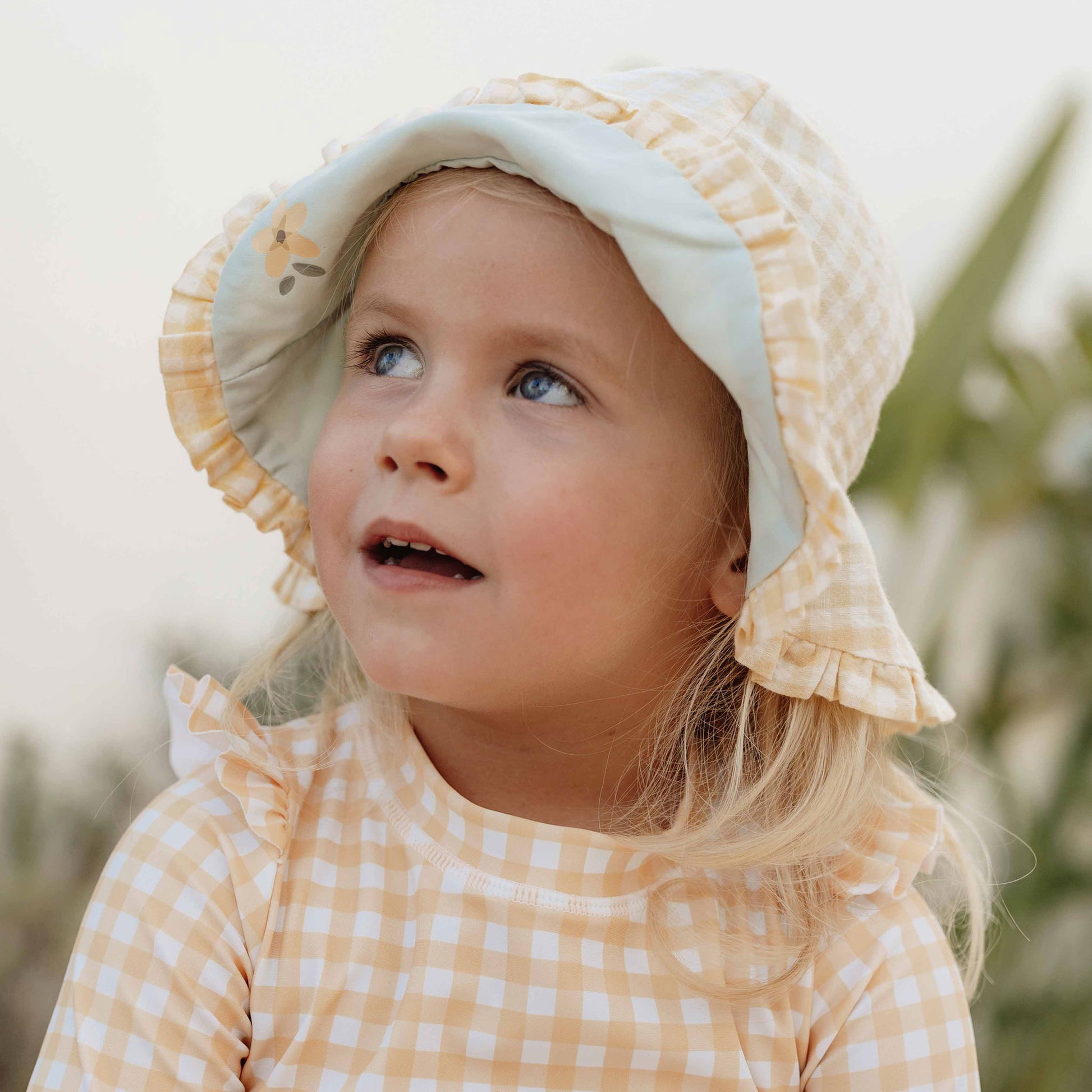 Little girl wearing Little Dutch Reversible Sun Hat In Sea Green & Sunshine Check