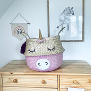 Unicorn-shaped storage basket on a wooden dresser with wall art in the background