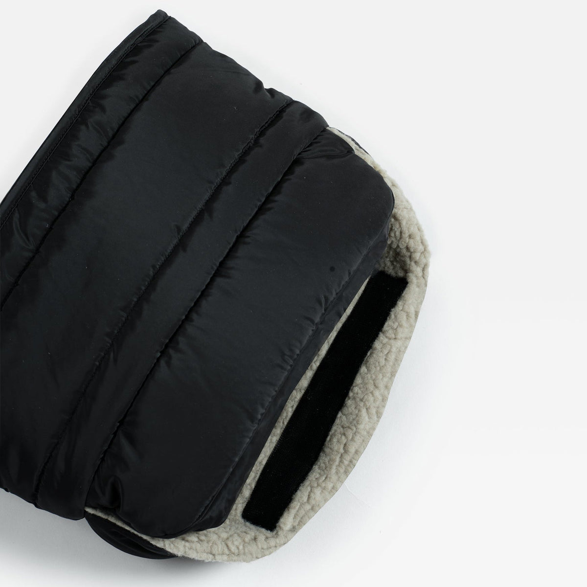 Close-up of a Finnson black quilted puffer Mono Mitten showing the black outer shell and a light beige sherpa lining.