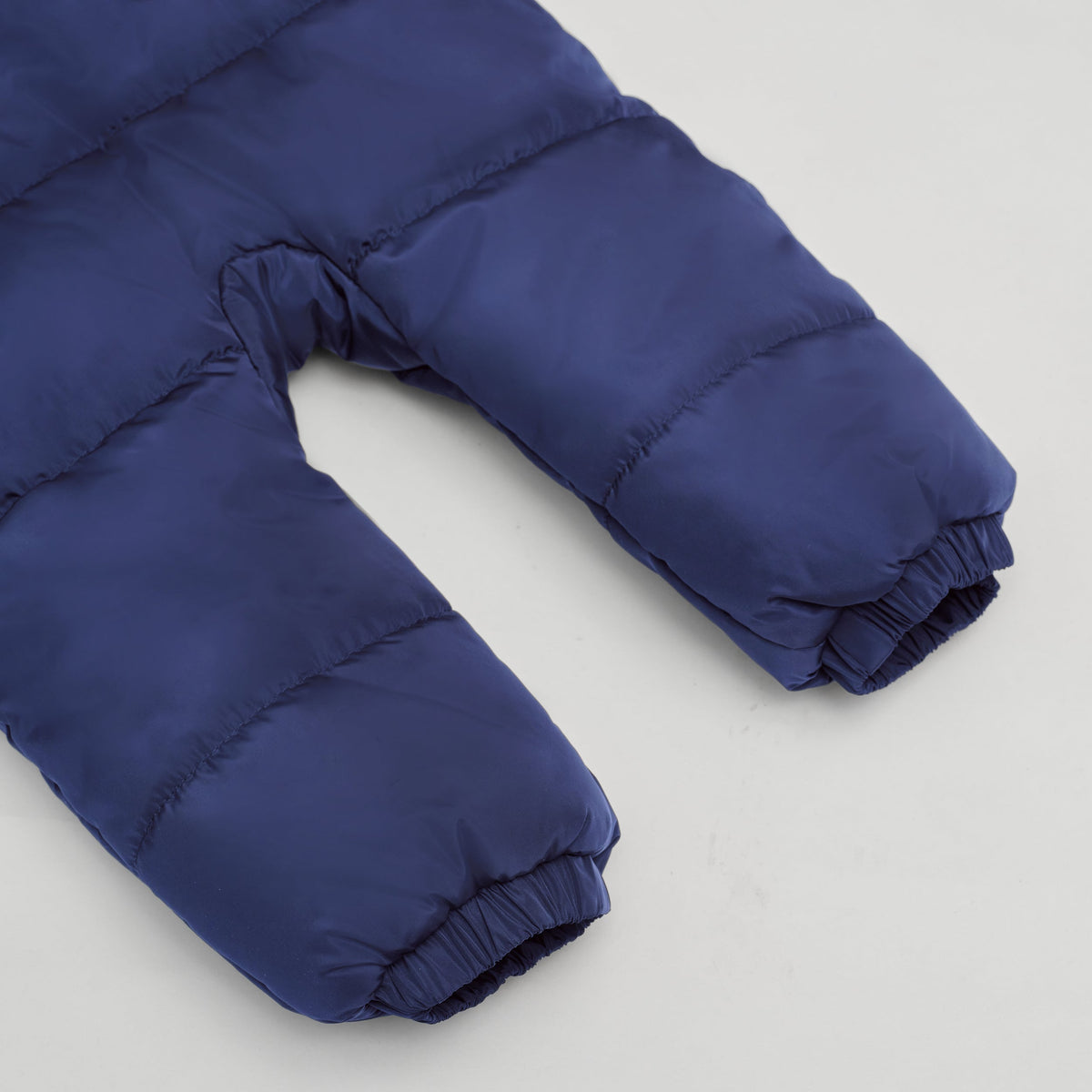 Close-up of a Finnson navy blue puffer snowsuit with elastic cuffs, shown on a white background.