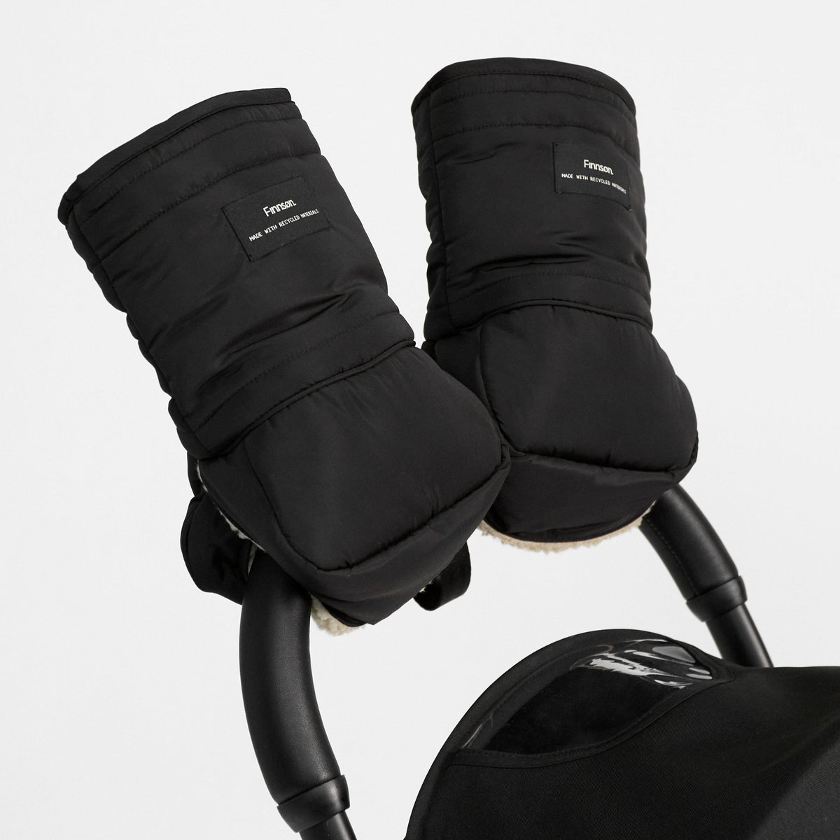 Black insulated stroller handwarmer sleeves with a small white 'frozen' brand patch, shown attached to a stroller handle against a light gray background.