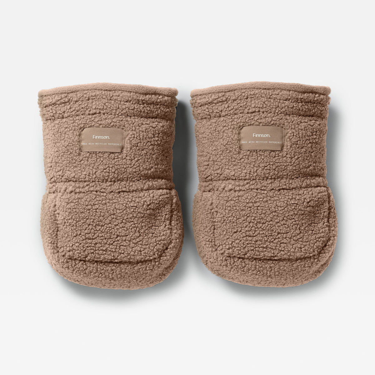 A pair of Finnson Stroller Mittens in a warm taupe-brown sherpa fleece, featuring a small tan brand patch on the front cuff. The booties are photographed from a top-down angle on a clean, light gray background.