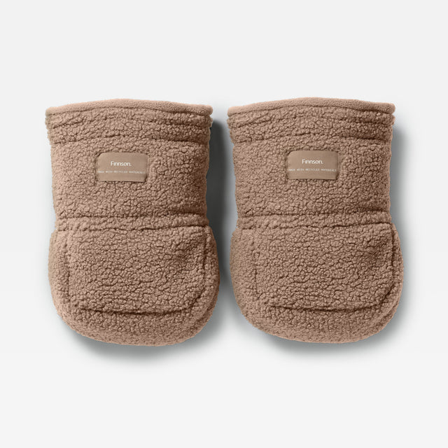 A pair of Finnson Stroller Mittens in a warm taupe-brown sherpa fleece, featuring a small tan brand patch on the front cuff. The booties are photographed from a top-down angle on a clean, light gray background.
