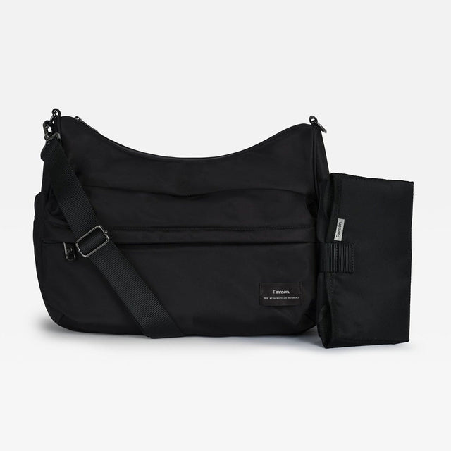A black changing shoulder bag with an adjustable shoulder strap and a matching zippered pouch attachment, shown on a light gray background.