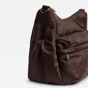 A Finnson dark brown changing shoulder bag with a subtle tonal pattern, featuring a drawstring side detail and a front zippered pocket, shown on a light gray background.