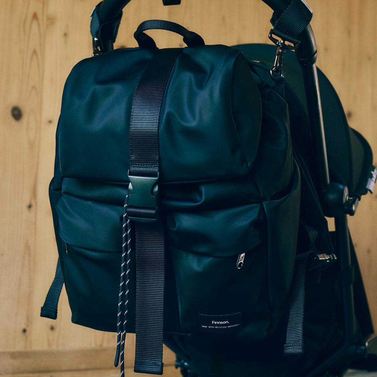 Finnson Black backpack attached to a stroller against a wooden background