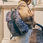 Women wearing a Finnson leopard print changing backpack and beige coat, standing outdoors.