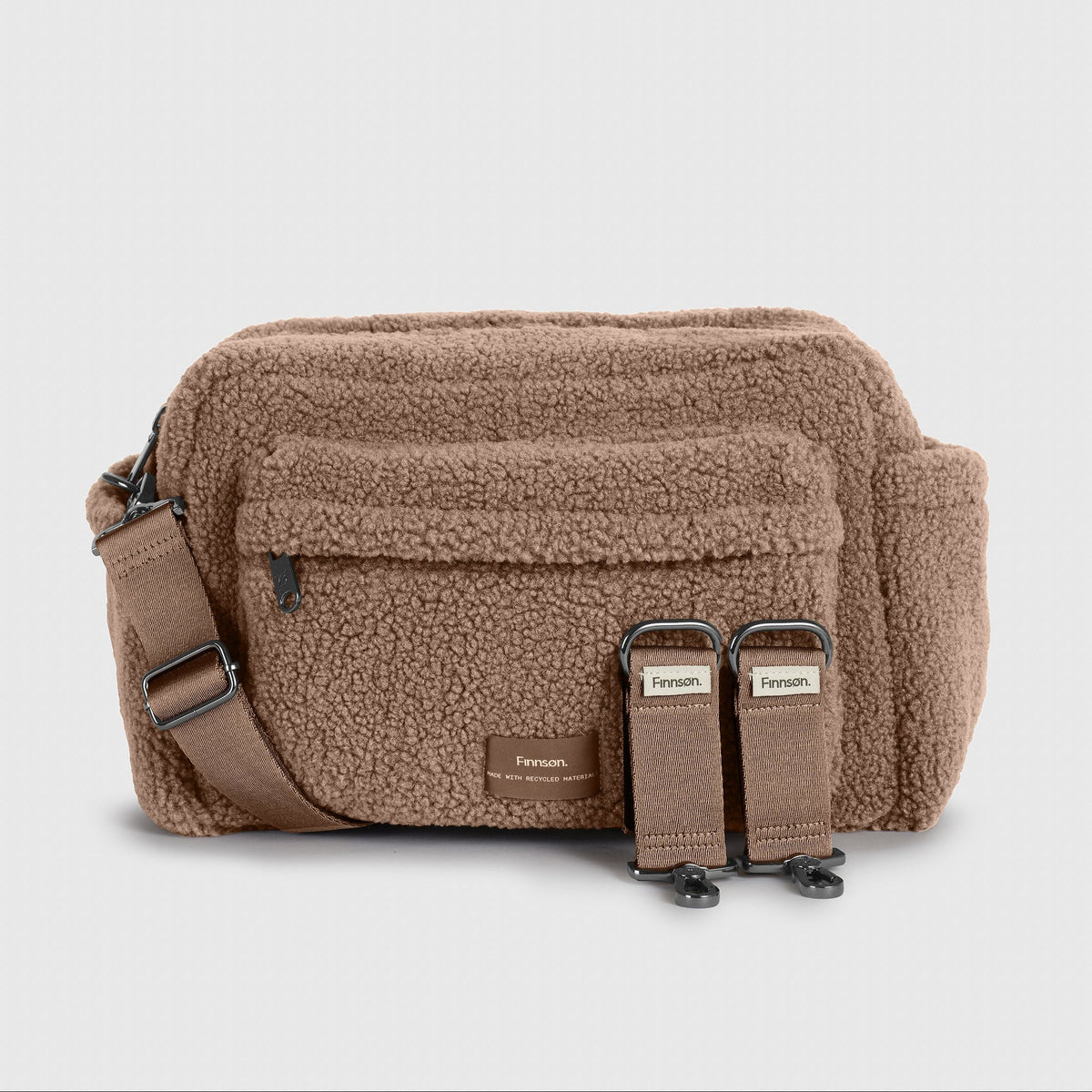 A Finnson brown mocha borg oversized stroller organiser bag with a front pocket, adjustable strap, and two included stroller clips, shown on a light gray background.