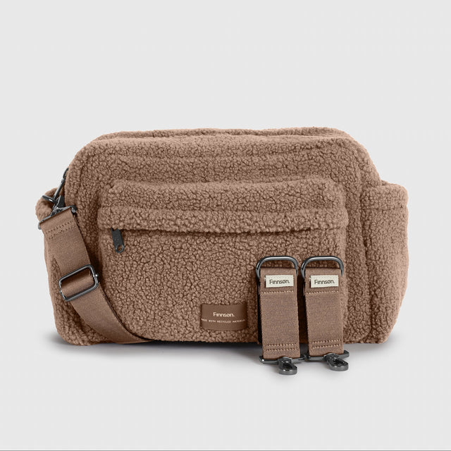A Finnson brown mocha borg oversized stroller organiser bag with a front pocket, adjustable strap, and two included stroller clips, shown on a light gray background.