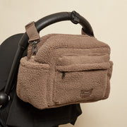 Finnson mocha brown borg oversized stroller organiser bag with stroller clips and a small brown brand patch, shown hanging from a black stroller handle against a plain beige background.