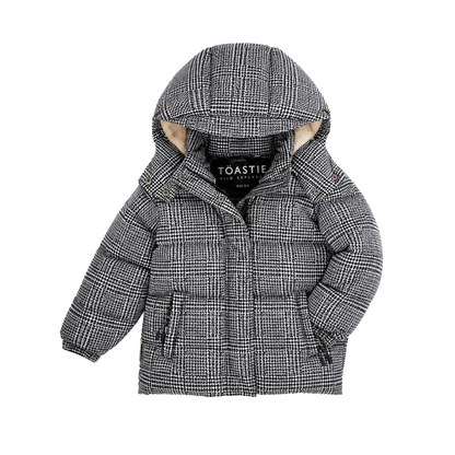 A children's hooded puffer jacket in a black and white plaid pattern with a beige faux-fur trim lining the hood, shown on a plain white background. The brand name 'TOASTIE' is visible on the inner neck label.
