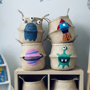 Woven baskets with colorful alien and space designs on a shelf against a space-themed wall.
