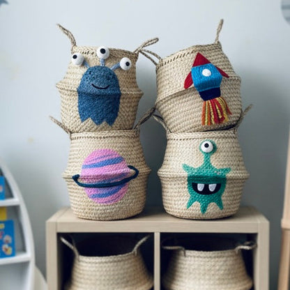 Woven baskets with colorful monster designs on a shelf against a space-themed wall.