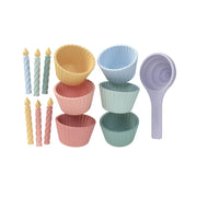 A set of pastel-colored silicone sensory cake shaped toys on a solid white background. The set includes six cupcake liners in yellow, blue, pink, and mint green, four twisted candle-shaped toppers in pastel blue, pink, and yellow, and a lavender-colored scoop.