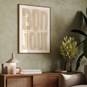 Wooden sideboard with decorative items against a green wall with a framed artwork with the word 'Bonjour'