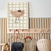 Wall-mounted coat rack with clothes and a decorative croissant art print in a room.