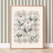 Framed artwork with a daisy design on a wall with striped wallpaper