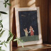 Framed artwork of two mice holding hands under a starry sky on a wooden shelf.