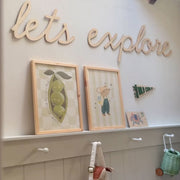 Wall with framed pictures, a sign saying 'let's explore', and two art prints