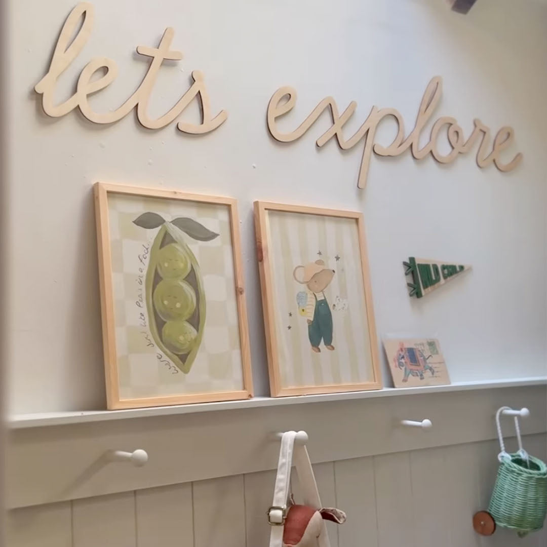 Wall with framed pictures, a sign saying 'let's explore', and two art prints