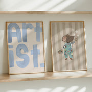 Two framed artworks on a shelf with 'ARTIST' and a cartoon mouse design.