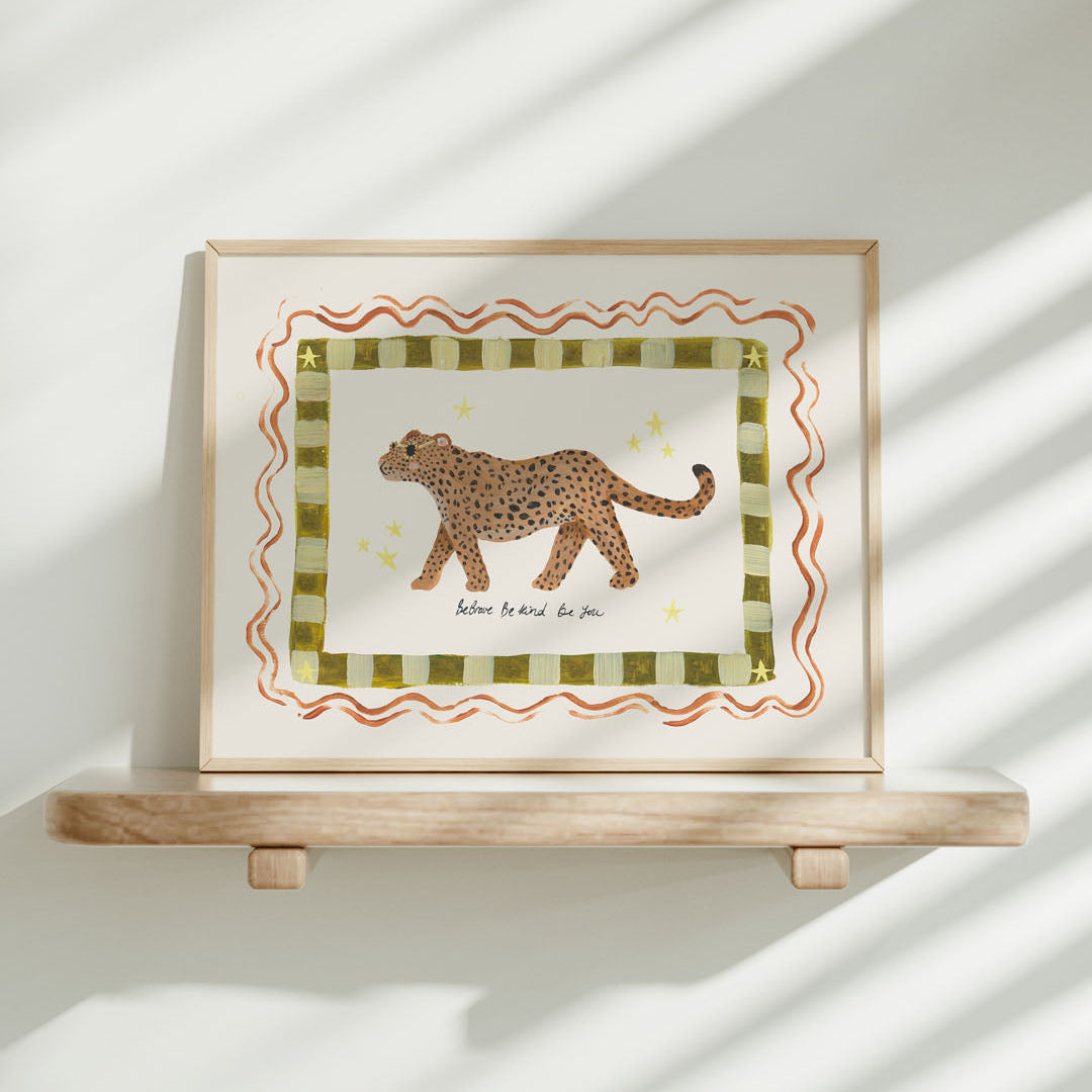 Framed artwork with a jaguar illustration and the phrase 'Be brave, be kind, be you' on a white wall
